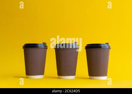 Three takeaway brown paper coffee cups with black plastic covers Stock Photo