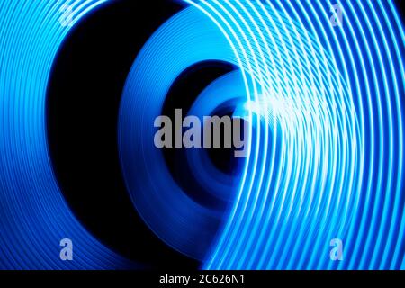A swirl of blue light painted in a corkscrew at night in this long exposure abstract photograph Stock Photo