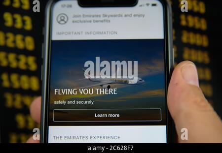 Viersen, Germany - July 6. 2020: Closeup of mobile phone with Emirates airlines flight booking app. Blurred departure board background. (Focus on plan Stock Photo