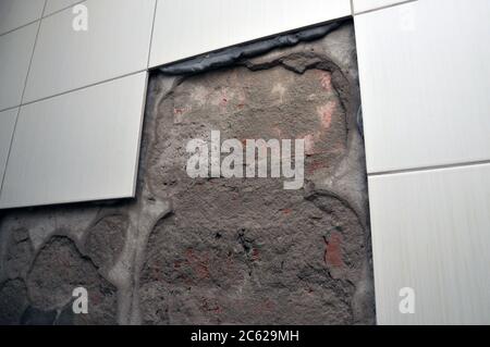 Wall of the toilet room with fallen off tiles, the defect of decoration Stock Photo