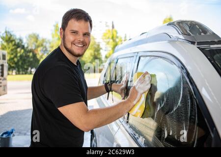 man cleaning car with yellow sponge. carwash concept