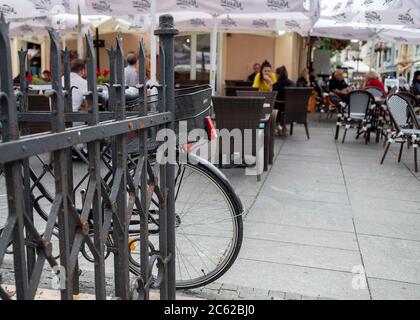 Belgrade, Serbia, June 18, 2020: Bicycle leaned on the fence near by street cafe at Magistrate Square (Magistarski Trg) in Zemun Stock Photo