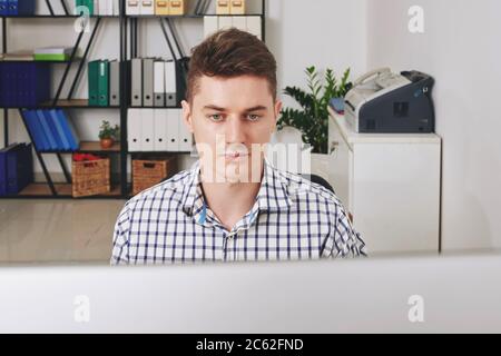 Serious young software developer working on computer in office Stock Photo