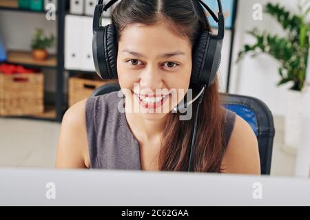 Customer support manager in headset smiling when answering questions of client Stock Photo