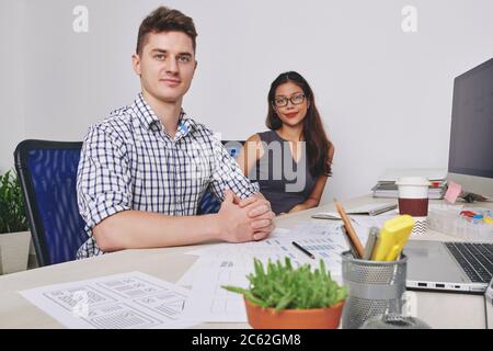Team of positive confident young ux designers working on project at office desk Stock Photo