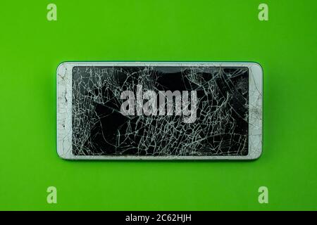 Smartphone screen is cracked on green background Stock Photo