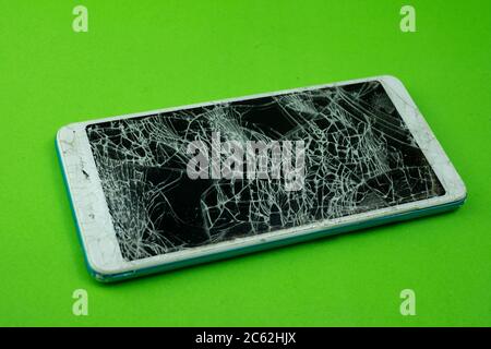 Smartphone screen is cracked on green background Stock Photo