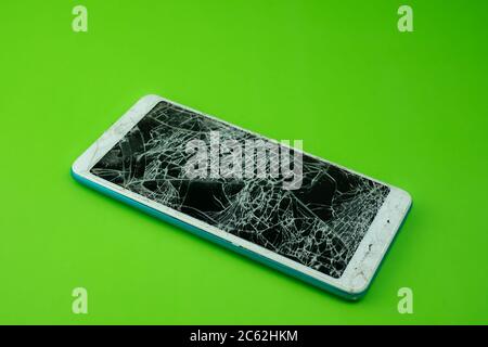 Smartphone screen is cracked on green background Stock Photo