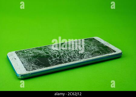 Smartphone screen is cracked on green background Stock Photo