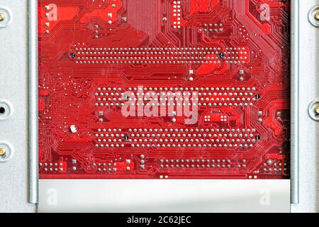 Red computer circuit board connected to the case. Hardware components. View inside, background, close-up Stock Photo