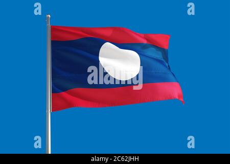 Laos national flag waving in the wind on a deep blue sky. High quality fabric. International relations concept. Stock Photo