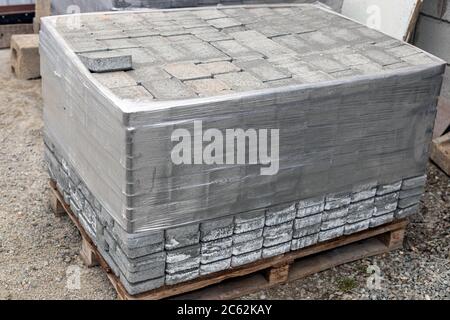 Pile of new grey paving stones on wooden pallet fixed with stretch wrap. Building material for the pavement reconstruction Stock Photo