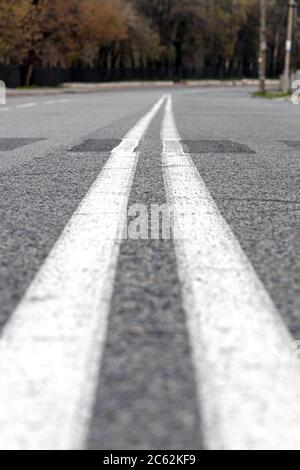 Close-up of double white continuous lines on empty asphalted road. Turn to the right on the road. Spring time, background Stock Photo