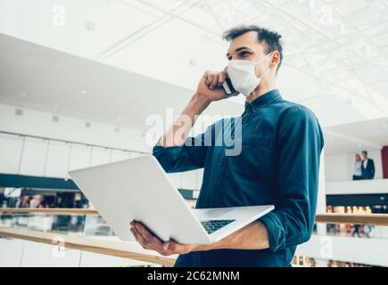 young man in a protective mask talking on a smartphone. Stock Photo