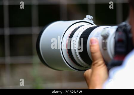 The telephoto lens in the hands of the photographer Stock Photo