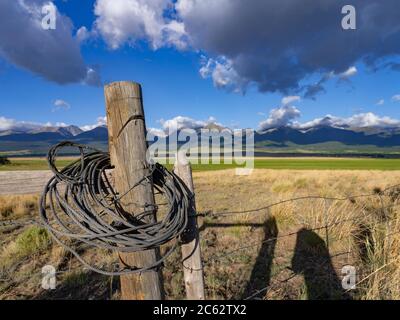 Old worn weathered fence post with rocky mountains in the background, Colorado, USA Stock Photo