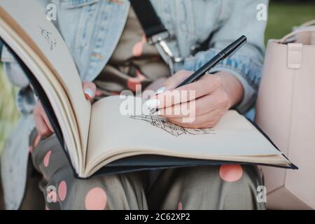 Sketchbook with a drawing of a house close-up. Girl draws in the fresh air. Front view Stock Photo