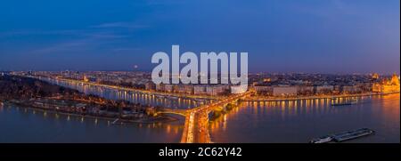 Panoramic Aerial drone shot of Margaret Bridge with lights on over Danube river during Budapest sunset Stock Photo