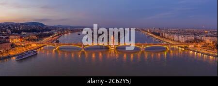 Panoramic Aerial drone shot of Margaret Bridge with lights on over Danube river during Budapest sunset Stock Photo