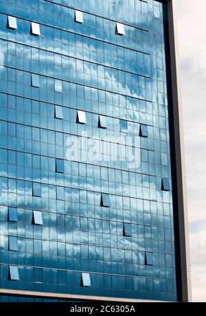 Blue sky and clouds reflection or reflections on modern office blue glass building facade as symmetrical architectural concept. Stock Photo