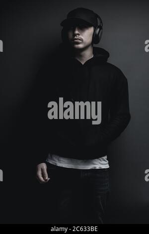 young cool rapper with black hoodie and cap listening music with headphones  Stock Photo - Alamy