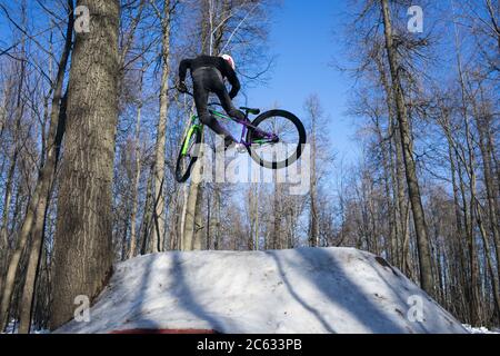 Mountain biker rider does a dirt jumping trick in the winter. Moto whip on bike Stock Photo