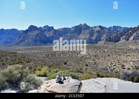 Red Rock Canyon seen from the high point overlook. Two small rock cairns in the foreground with desert foliage and mountains that rise in the distance Stock Photo