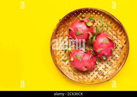 Ripe dragonfruit or pitahaya in wooden bamboo threshing basket on yellow background. Copy space Stock Photo