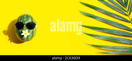 Watermelon with sunglasses and tropical palm leaves on yellow background. Enjoy summer holiday concept. Stock Photo