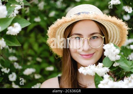 young woman in a summer hat walks among the flowering trees Stock Photo