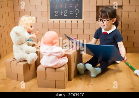 toddler girl pretend play as a teacher at home Stock Photo
