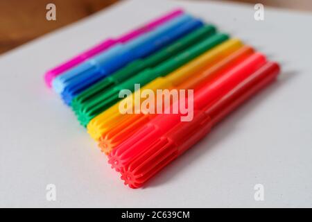 Colored markers on a white sheet and brown table. Stock Photo