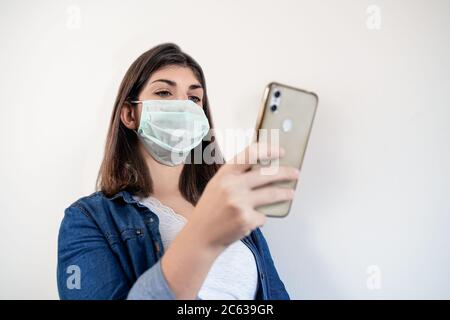 Portrait of woman with medical protection mask using her smartphone. Stock Photo