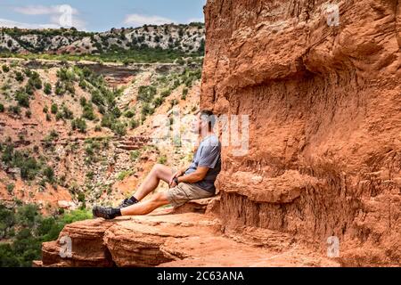 Man sitting on the edge of the Lighthouse Rock, Palo Duro Canyin State Park, Texas Stock Photo