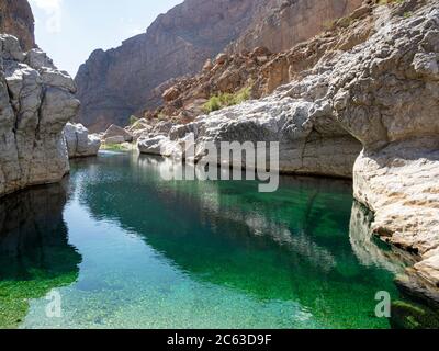 Naturally formed swimming pools in front of the town of Bidah, Wadi Bani Khalid, Sultanate of Oman. Stock Photo