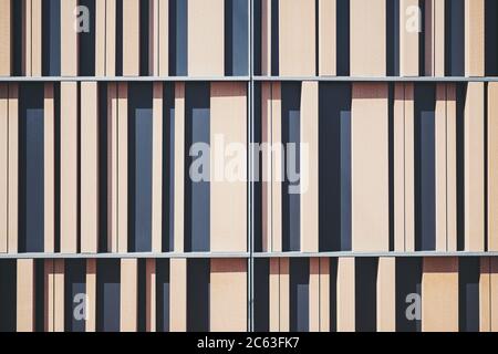 Frontal view of an abstract wooden and metal contemporary building facade with vertical stripes of timbers of different form and thickness Stock Photo
