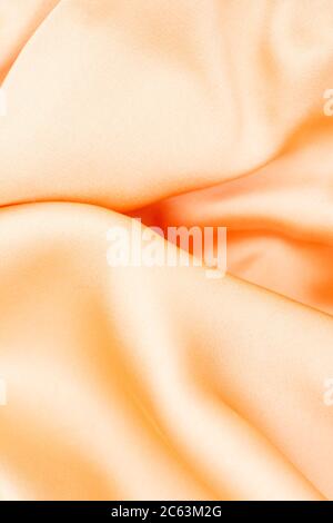 Fabric golden in natural silk. Peach smooth silk fabric. Close-up yellow beige cloth. Fold fabric Stock Photo