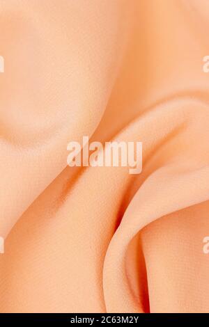 Fabric golden in natural silk. Peach smooth silk fabric. Close-up yellow beige cloth. Fold fabric Stock Photo