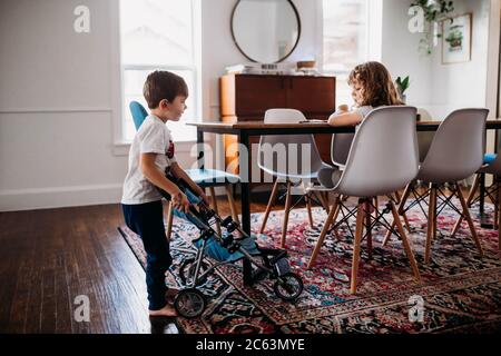 Young brother showing stuffed animal in stroller to sister at home Stock Photo