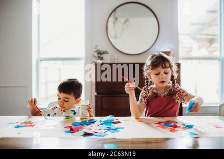 Brother and sister creating art together at home in spring Stock Photo