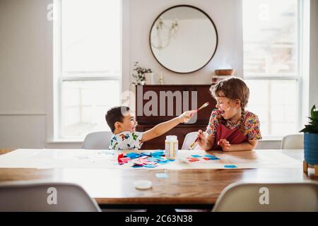 Young brother and sister doing arts and crafts at home in spring Stock Photo
