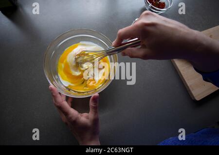 Overhead view of someone whisking milk into eggs in a bowl. Stock Photo