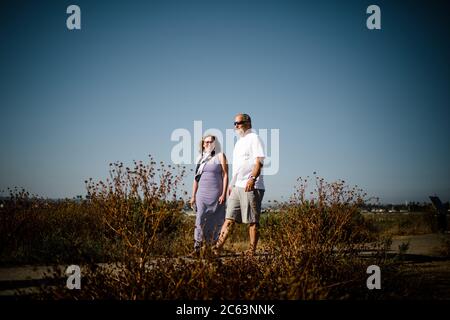 Baby Boomer Couple Smiling and Walking Along Sand Dunes Stock Photo