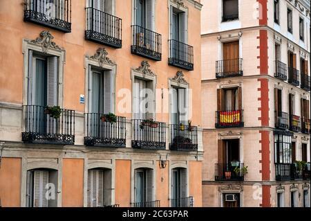 Details of exterior of colorful residential buildings with stone walls and metal balconies in Madrid Stock Photo