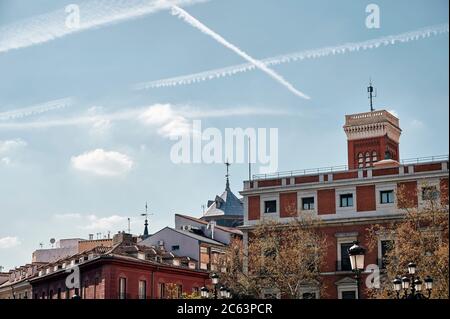 Low angle of scenic cityscape of historic buildings with red facade located in Madrid against blue sky Stock Photo