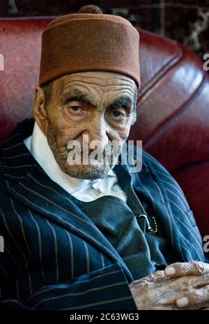 An elderly Kurdish man wearing a red felt Fez hat and pinstripe suit in the city of Dogubeyazit, in the eastern Anatolia region of Turkey. Stock Photo