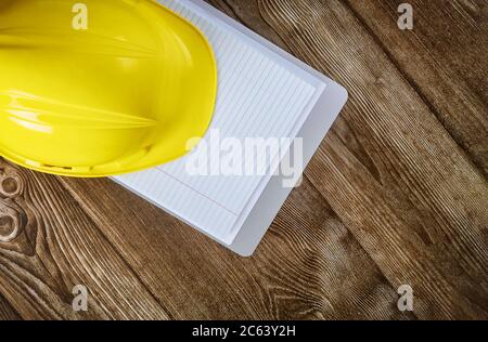 Engineer working on office desk with blank notebook construction protective yellow safety helmet on wood table Stock Photo
