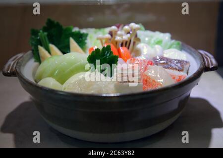 Sukiyaki or Japanese-style nabe. There are many seafood and vegetables in a clay pot. Stock Photo