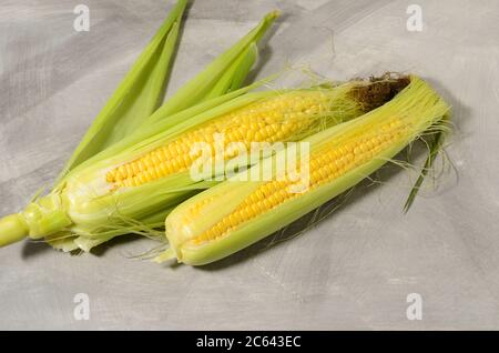 A ripe corn cob with leaves and yellow grains. Texture surface as a background. Stock Photo