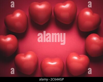 Red hearts on red background with copy space. Wreath made from many red ball foam with heart shape. Love, care, and Valentine Day round border concept Stock Photo